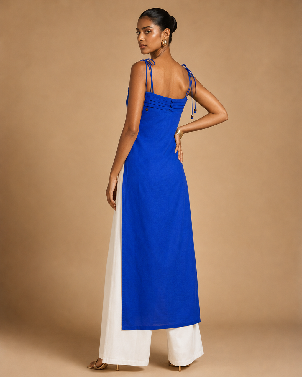 Back view of cobalt blue Myra pintuck kurti with covered buttons and tie-up beaded straps over white palazzo